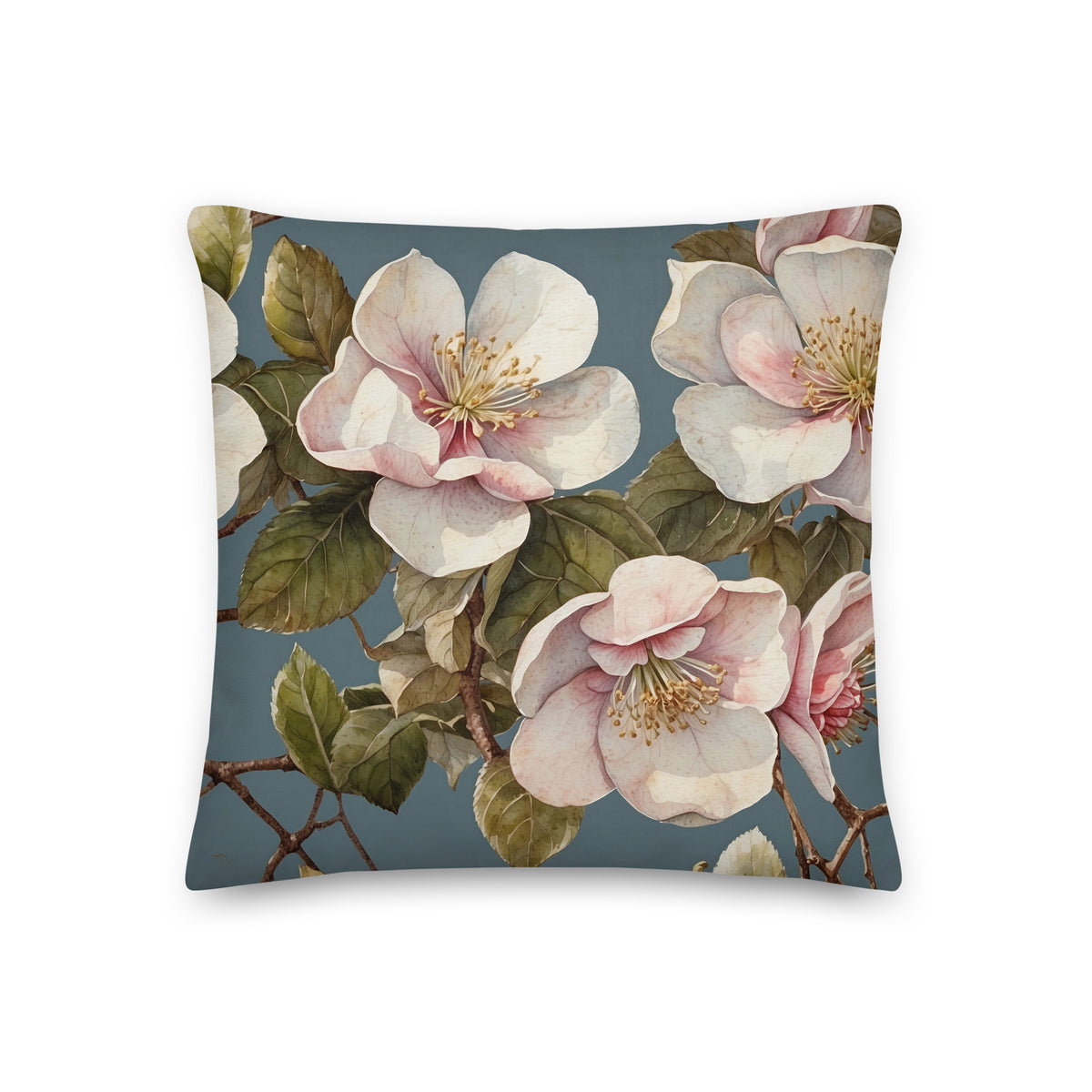 Botanical cushion with large blush-pink and ivory blossoms, olive-green leaves and branches on a dusty blue background.