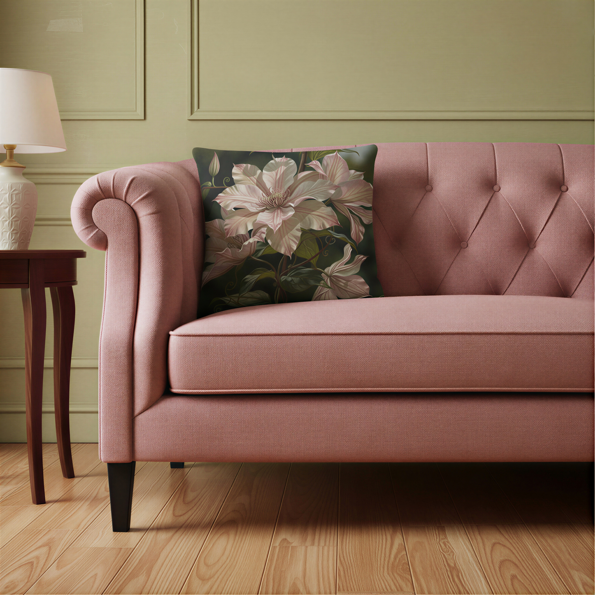 Square decorative cushion featuring large pale blush-pink clematis flowers with layered petals, green leaves and climbing stems against a deep forest-green background.